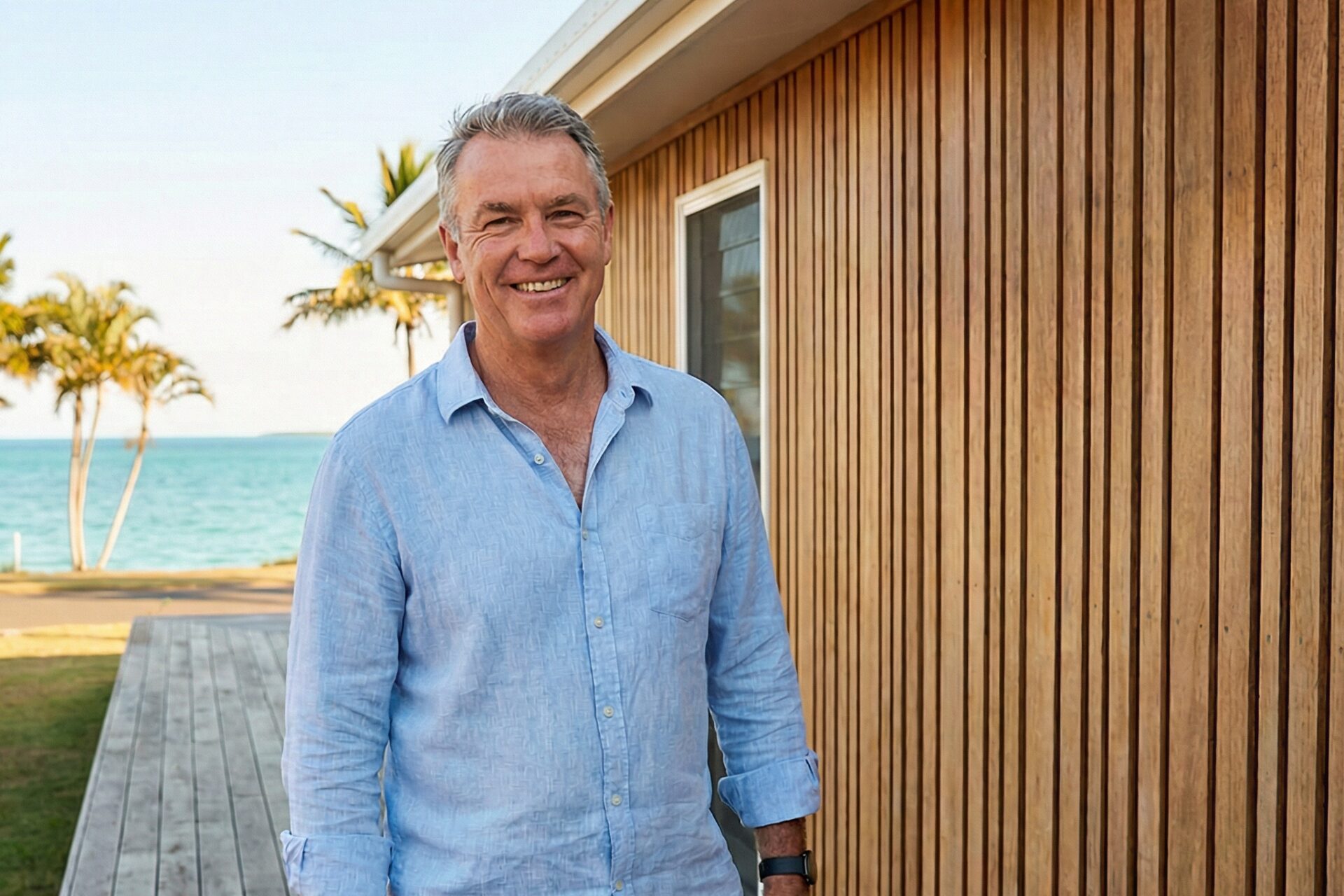 Smiling man outdoors near wooden building and sea
